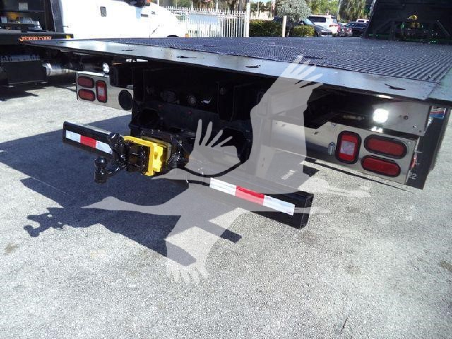 Back of a Freightliner M2 106 rollback truck showing tow hitch, yellow towing mechanism, rear lights, and flatbed undercarriage.