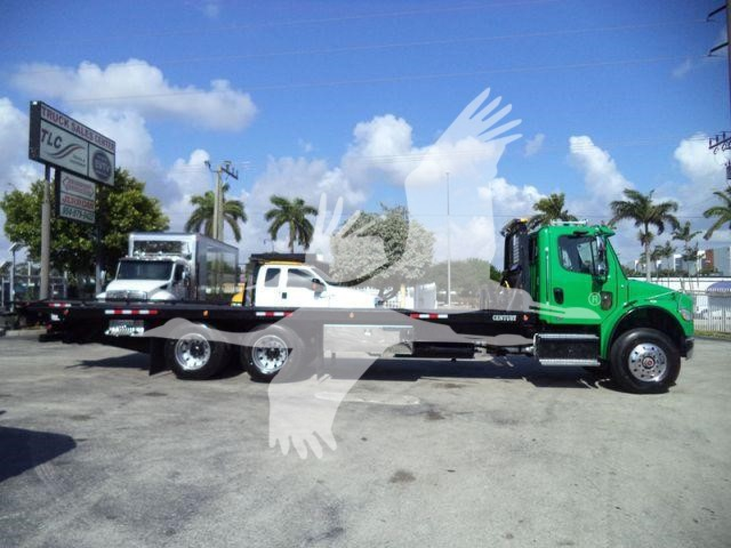 2016 Freightliner M2 106 rollback truck in a parking lot, green-colored cab, long flatbed trailer, palm trees in background.
