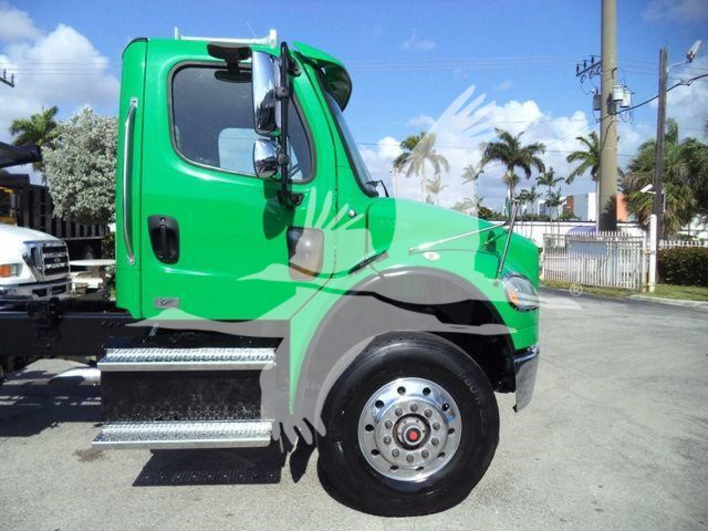 Freightliner M2 106 truck side view showing green cab and chrome steps, front wheel, and side mirror.