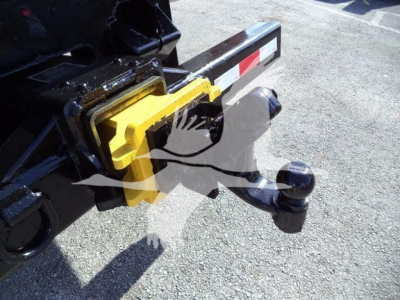 Truck hitch with yellow safety latch and ball hitch assembly on a Freightliner M2 106 tow/Tow hitch. Visible components include yellow locking mechanism and black hitch ball.