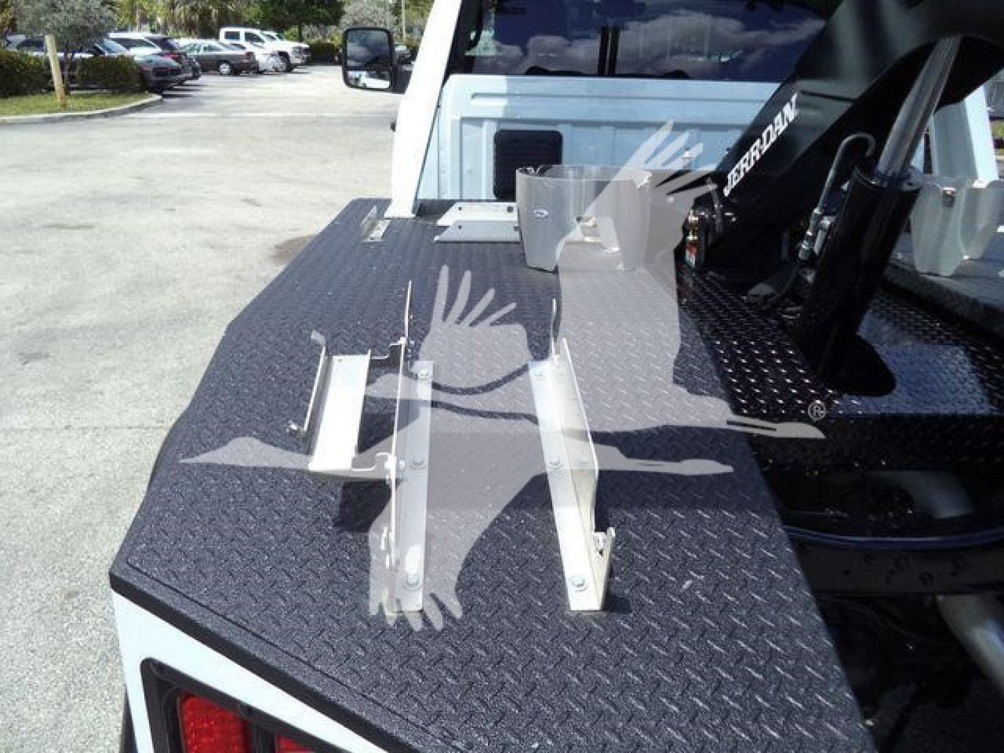 Truck bed with diamond plate flatbed and mounting brackets, Ram winch setup partially visible in background, rear of cab seen.