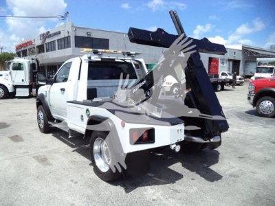 Ram 4500 tow truck rear view showing hydraulic lift and winch mechanism with white cab and bed in an outdoor lot.