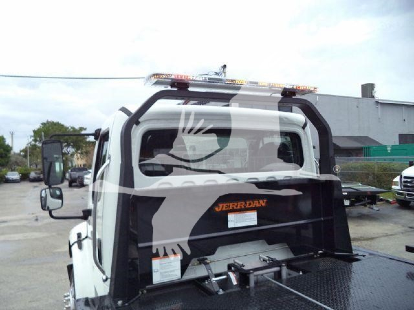 Back of a Freightliner M2 106 rollback truck showing rear cab window, black rest area, and tool bed. Visible text includes 'JERBAN' (on the cab) and small labels on the rear panel.