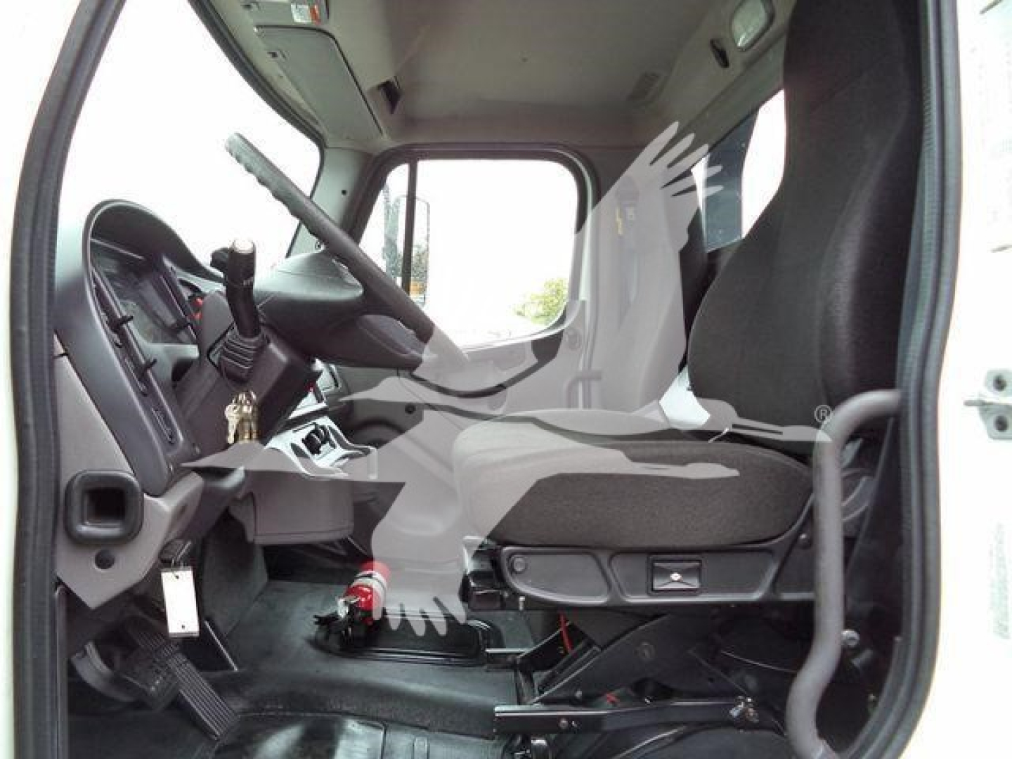 Truck cab interior of a 2020 Freightliner M2 106 rollback unit showing driver seat and dashboard with steering wheel, pedals, and gear selector.