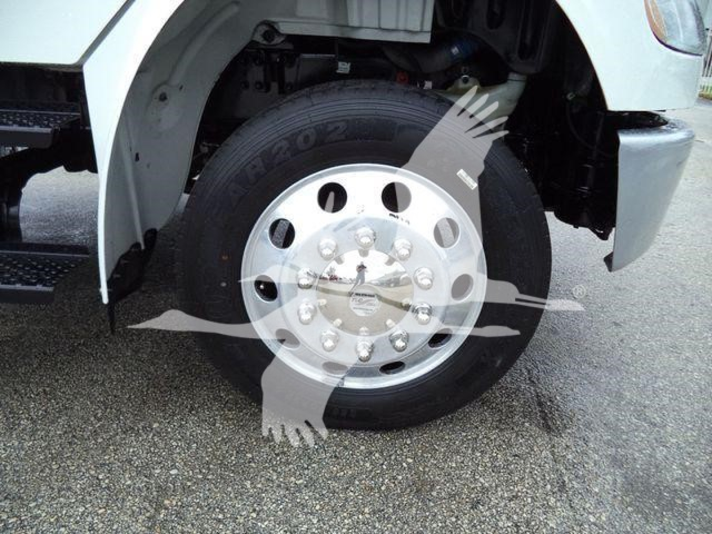 Front wheel and fender of a Freightliner M2 106 truck showing a steel wheel with hub caps and tire.
