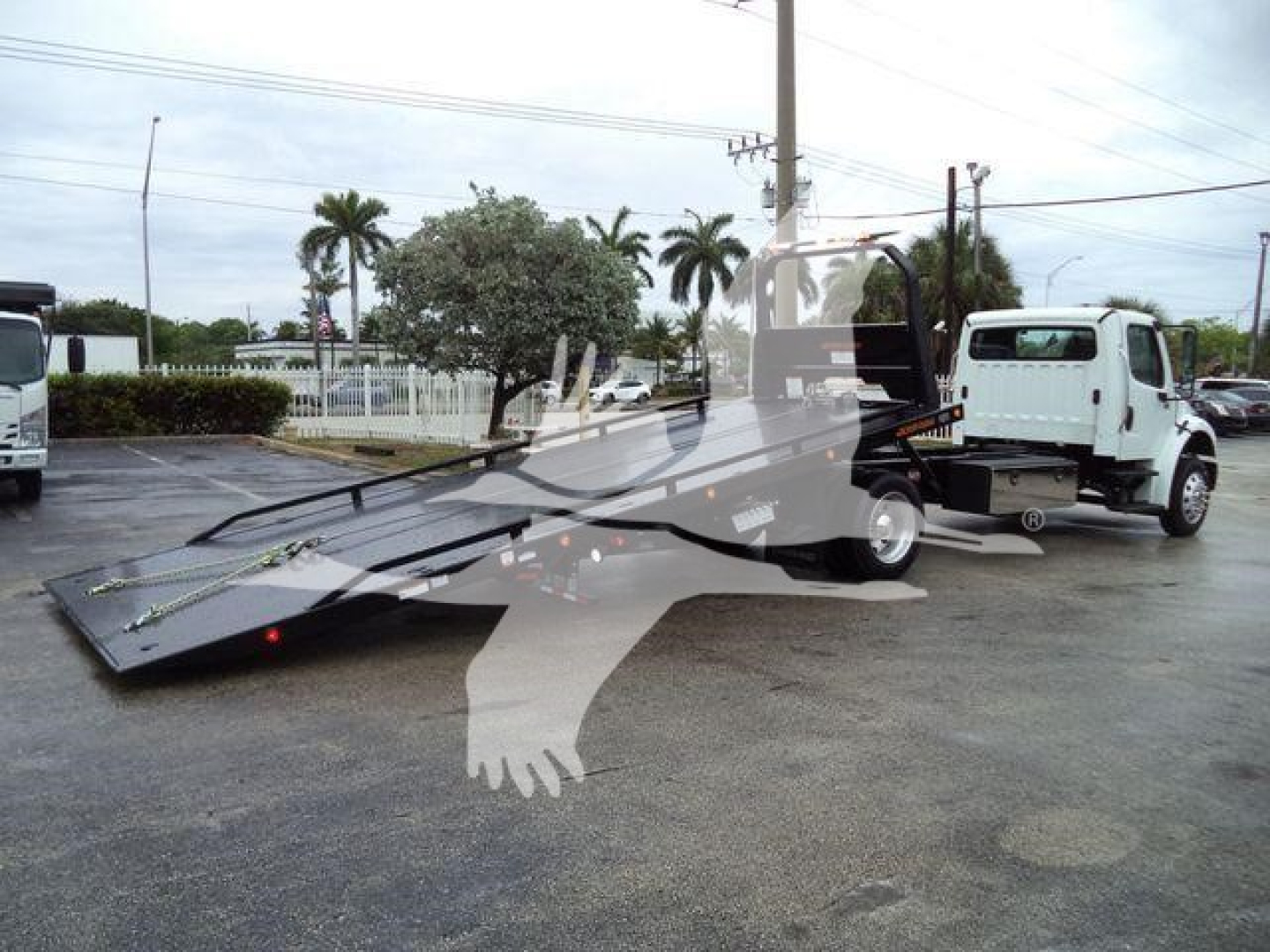 Truck ramp tow truck setup showing rollback with hydraulic ramp and forklift-style platform, Freightliner M2 106 in view