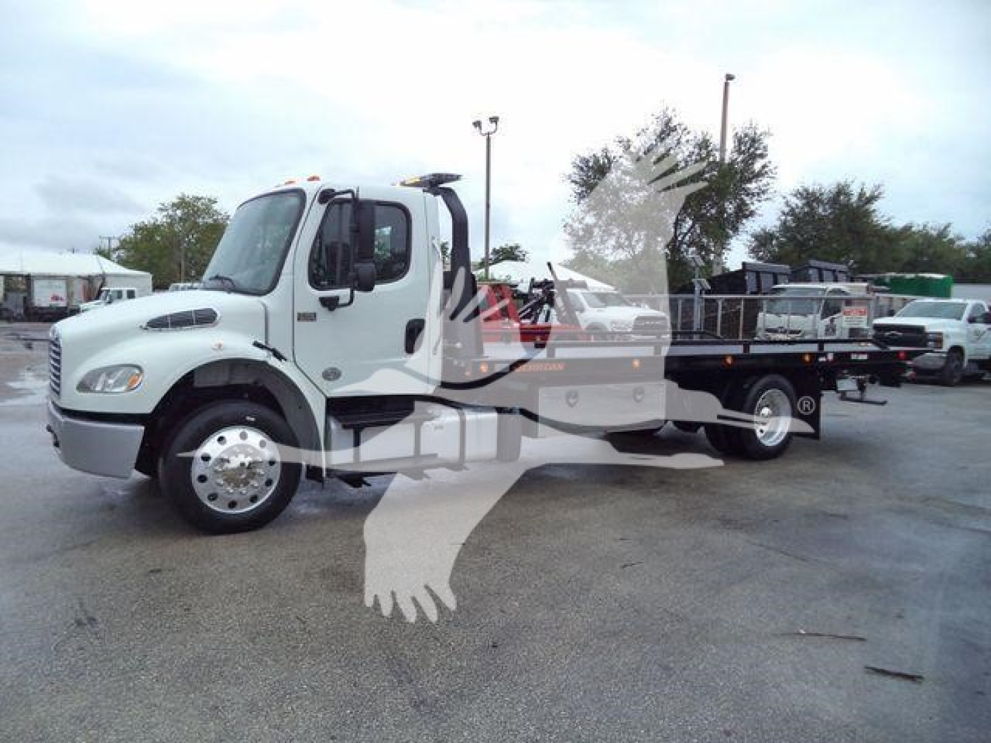  Freightliner M2 106 rollback truck showing side view with white cab and flatbed, stock number visible in listing.