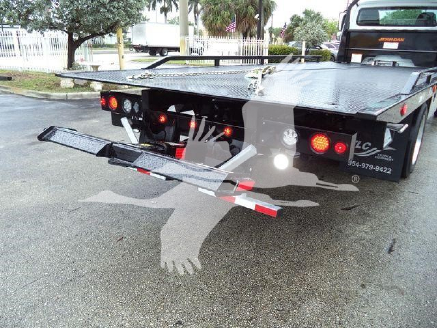 Rear view of a Freightliner rollback truck bed with folded double-tier lift/ramps and taillights visible.