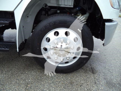 Front wheel and fender of a Freightliner M2 106 truck showing a steel wheel with hub caps and tire.