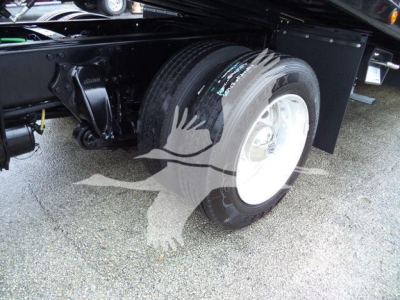 Truck rear wheel and suspension components of a Freightliner M2 106 rollback truck, with dual rear wheels and black undercarriage visible.