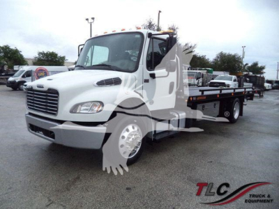 Flatbed rollback truck in white with a long wheelbase and chrome grille, Freightliner M2 106 chassis.