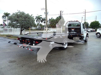 Truck bed with rollback equipment on a Freightliner M2 106 showing flatbed and rear lighting.