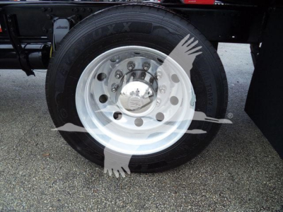 Wheel close-up on Freightliner M2 106 rollback chassis showing aluminum wheel with hubcap and tire sidewall marking.