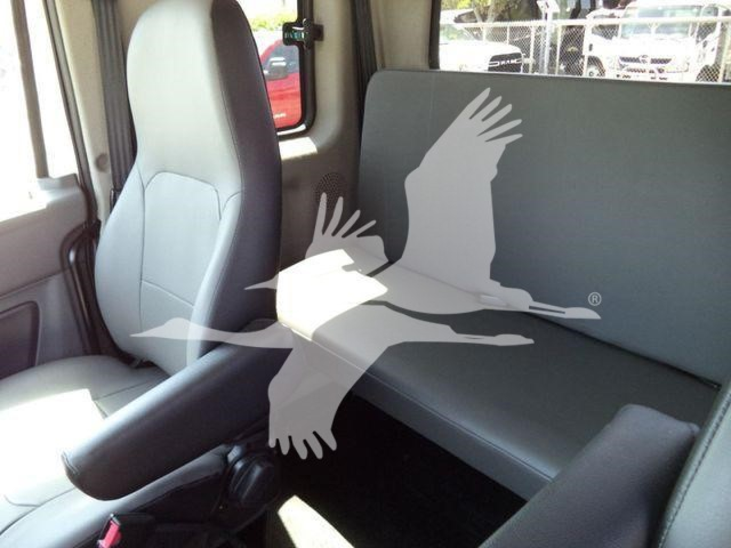 Cab interior of a 2027 International MV rollback truck showing front seat and rear bench with grey upholstery.