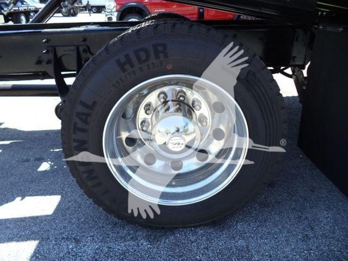 Truck wheel and tire showing chrome hub with lug nuts and heavy tread tire in a rollout truck.