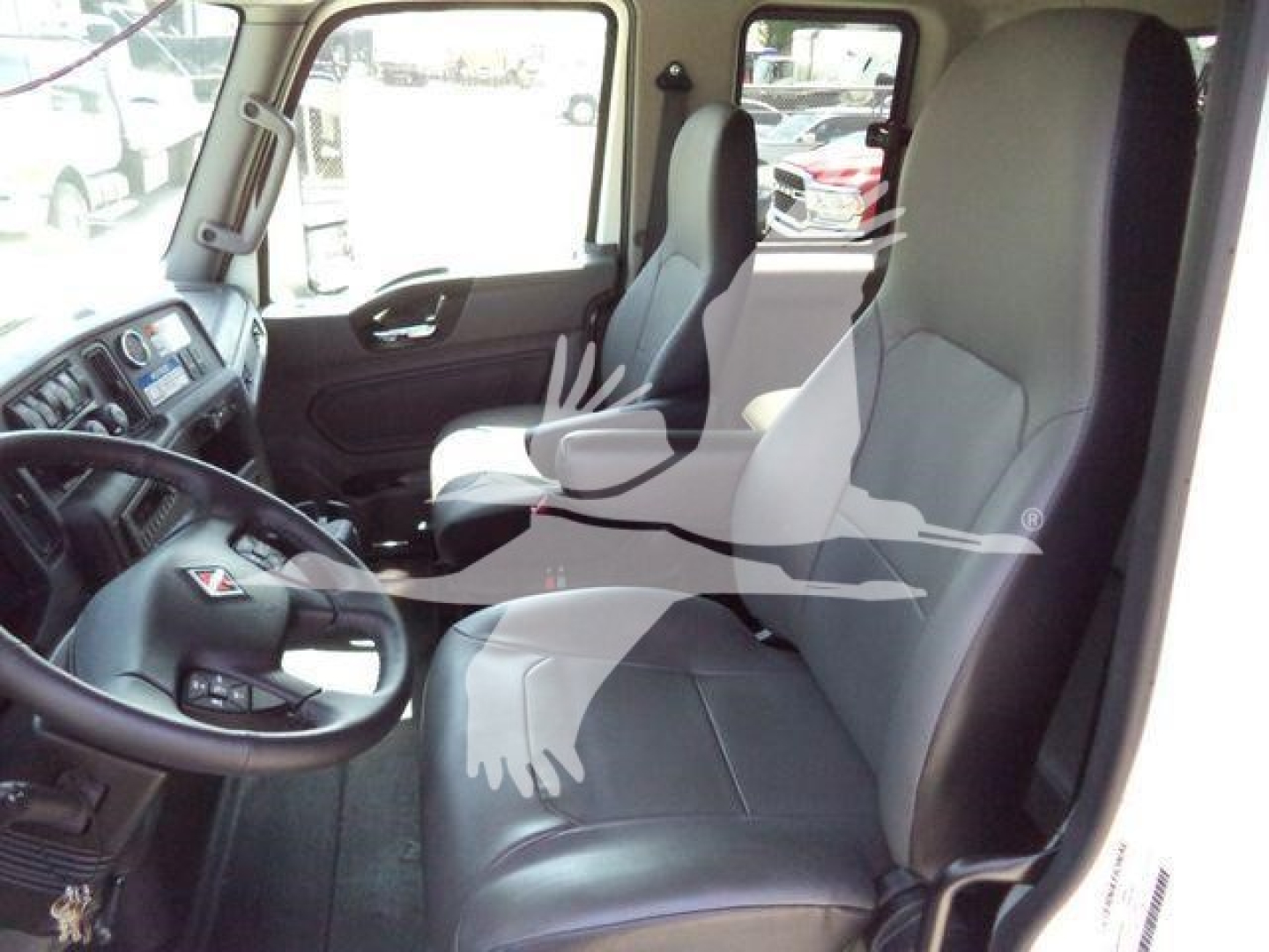Interior of a 2027 International MV rollback truck cabin with steering wheel, driver and passenger seats, dashboard, and side window.