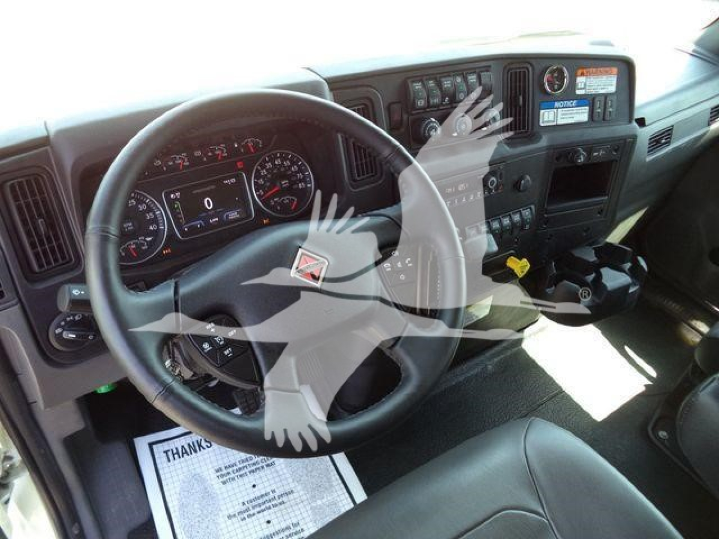 Truck cab interior with steering wheel, dashboard gauges, and center console visible.