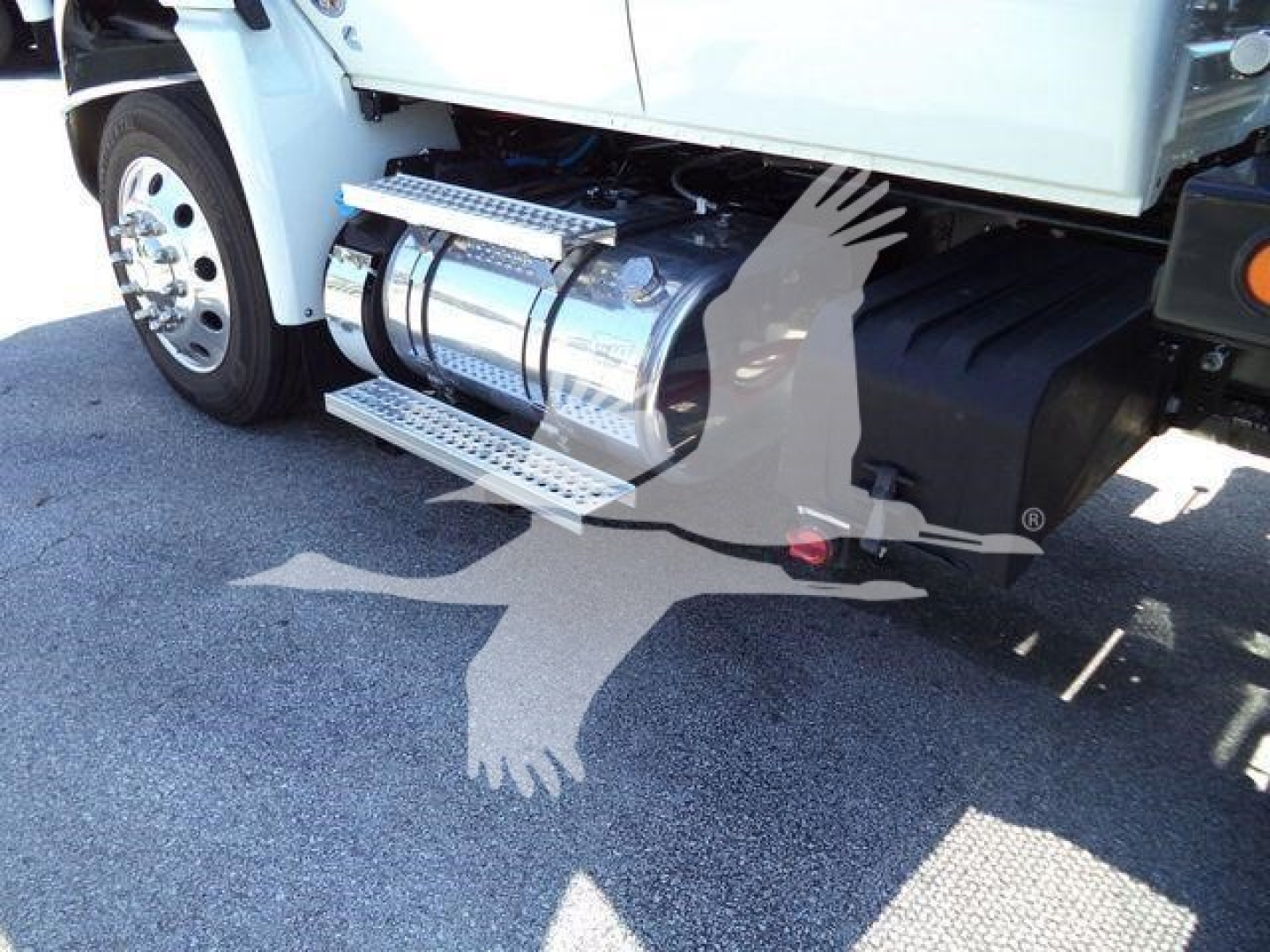 Truck side step and fuel tanks under a New International MV rollback truck showing chrome cylindrical fuel tanks and aluminum side steps.