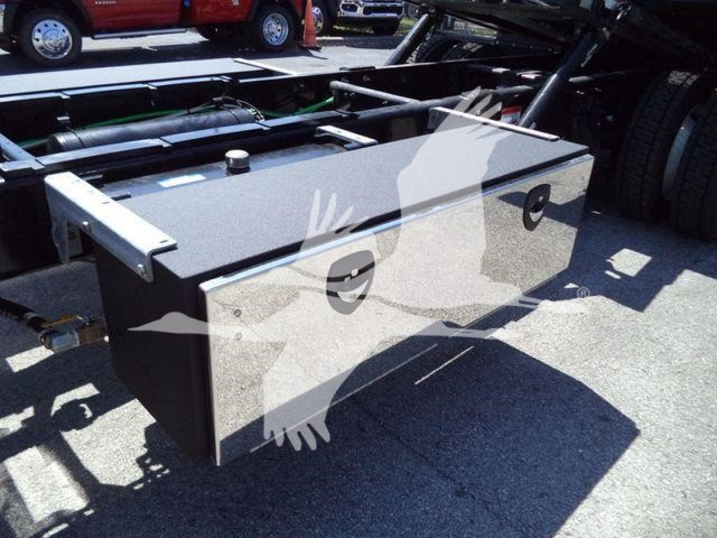 Truck chassis with a large rectangular aluminum fuel tank or toolbox mounted behind cab on a International MV rollback truck, shown from side angle.