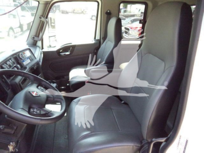 Interior of a 2027 International MV rollback truck cabin with steering wheel, driver and passenger seats, dashboard, and side window.
