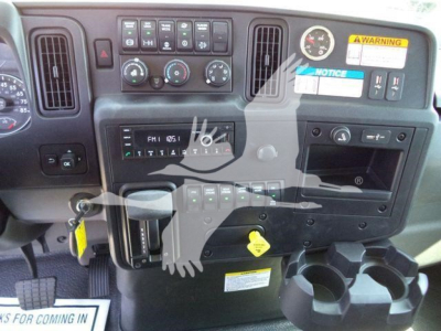 Dashboard and center console of a 2027 International MV rollback truck showing control panel, gauges, cup holders, and warning labels.