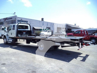 Flatbed rollback tow truck in a dealership lot showing International MV chassis and towing bed, stock number J18825.