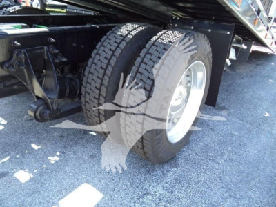 Vehicle chassis and dual rear tires of a rollback truck showing rear axle, suspension, and tire treads.