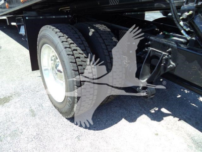 Truck rear wheel and chassis undercarriage with dual tires and suspension components visible.
