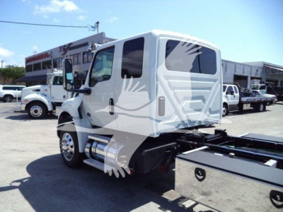 Truck cab and chassis rear view showing International MV series cab and rollback bed mounting area.