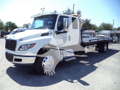 Truck cab and rollback bed showing International MV series with flatbed for towing and loading equipment.