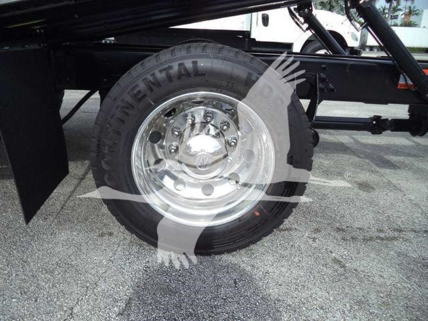 Truck wheel and tire close-up showing Continental tire mounted on polished steel rim under truck chassis.