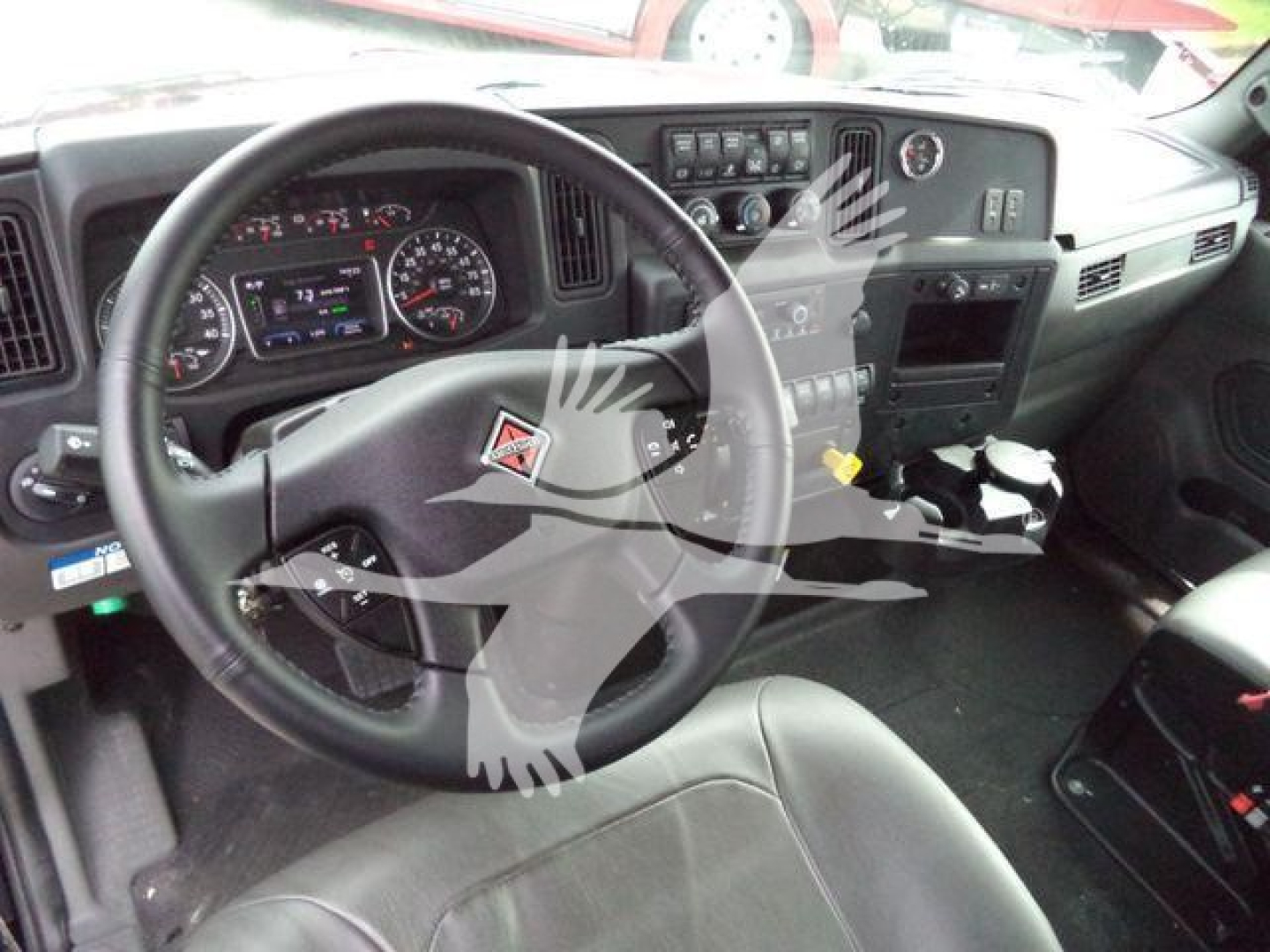 International MV truck cockpit showing steering wheel, dashboard gauges, and center console area.