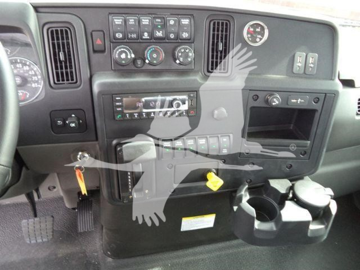Dashboard view of a truck cab showing instrument cluster, control panel, climate knobs, radio, auxiliary switches, and cup holders.