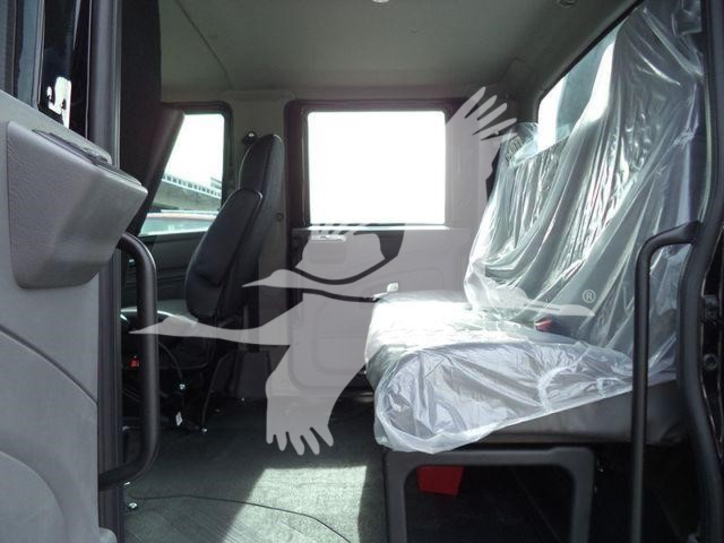 Interior of truck cab with plastic-covered seat, front seats visible and driver area, window at rear, rollover rollback category truck.