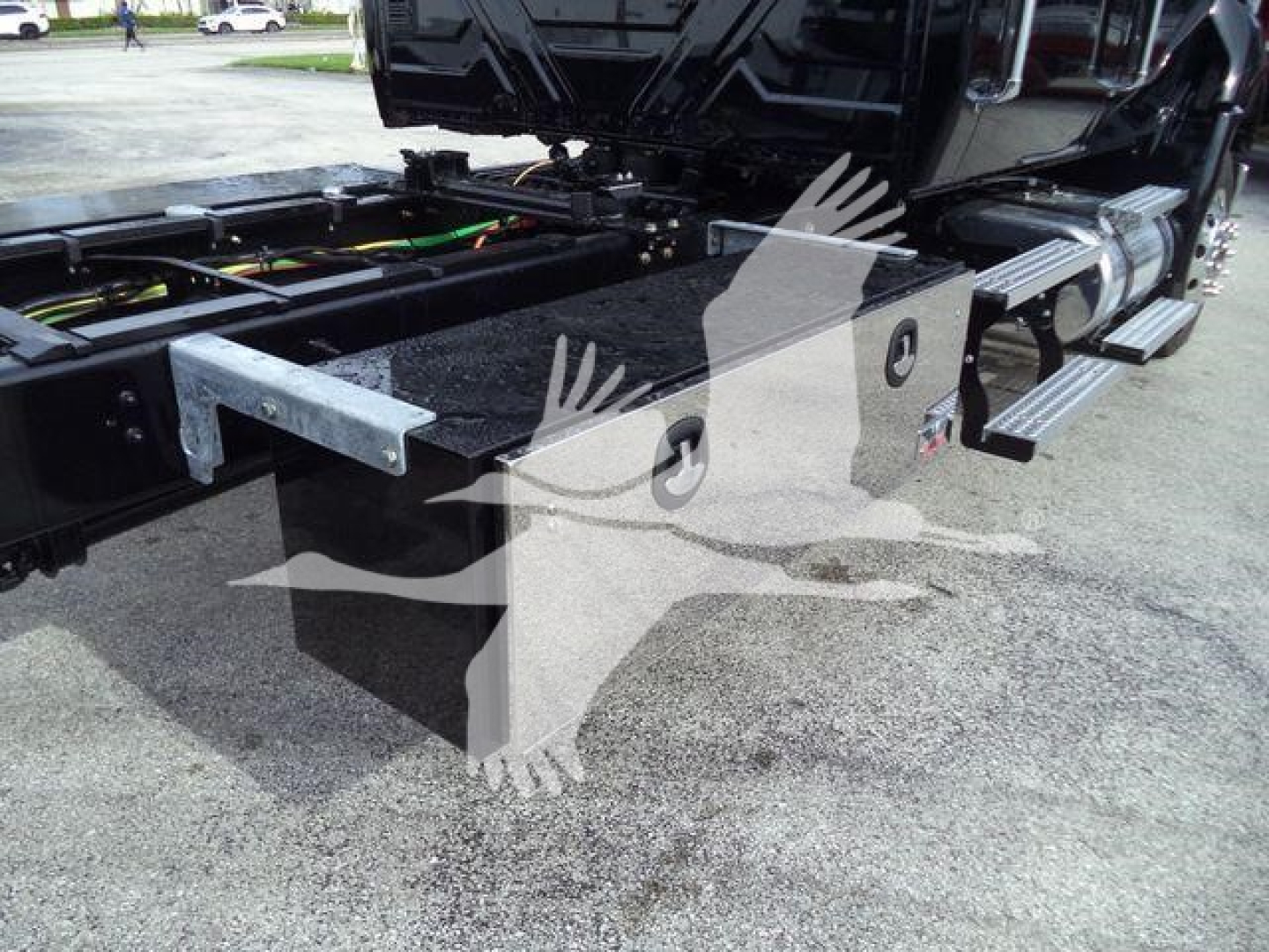 Truck chassis and side steps of a 2026 International MV rollback truck, showing undercarriage frame, hydraulic lines, and metal step rails.
