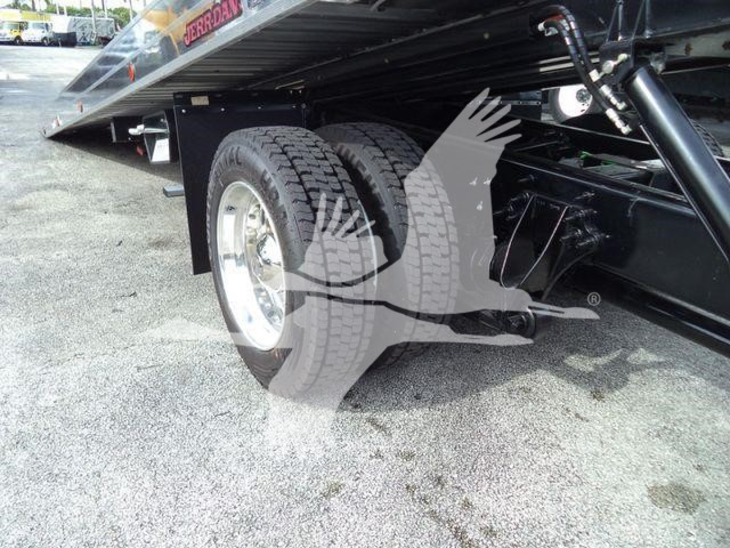 Dual rear wheels under a rollback tow truck chassis with hydraulic flatbed; visible text includes 'JERROn' or 'JERDON' on the bed edge and structural components.