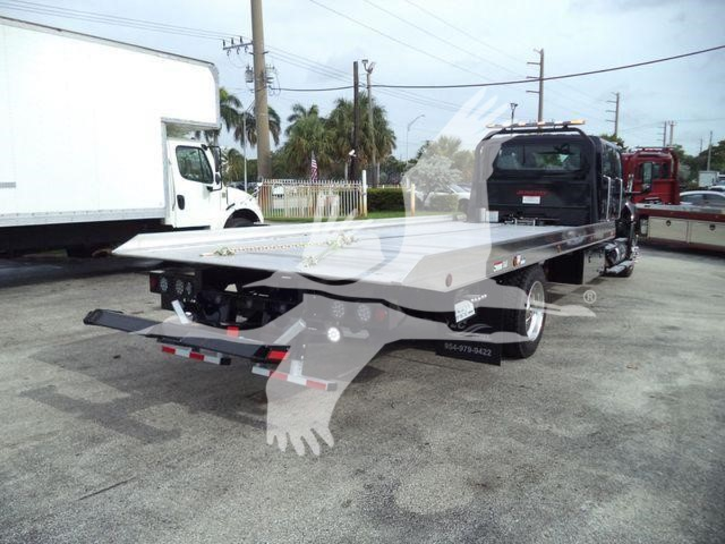 Tow truck rollback bed on a new 2026 International MV, side and rear view with branding and rear hitch lines.