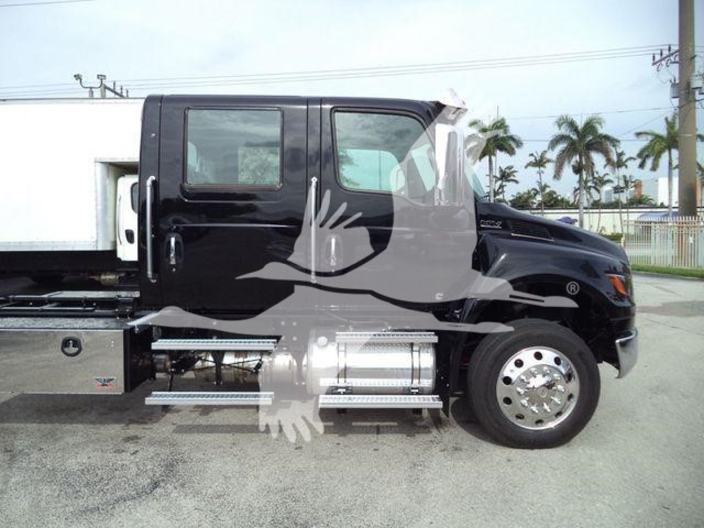 Truck side view of a black 2026 International MV rollback truck showing cab, fuel tanks, steps, and chrome wheels.