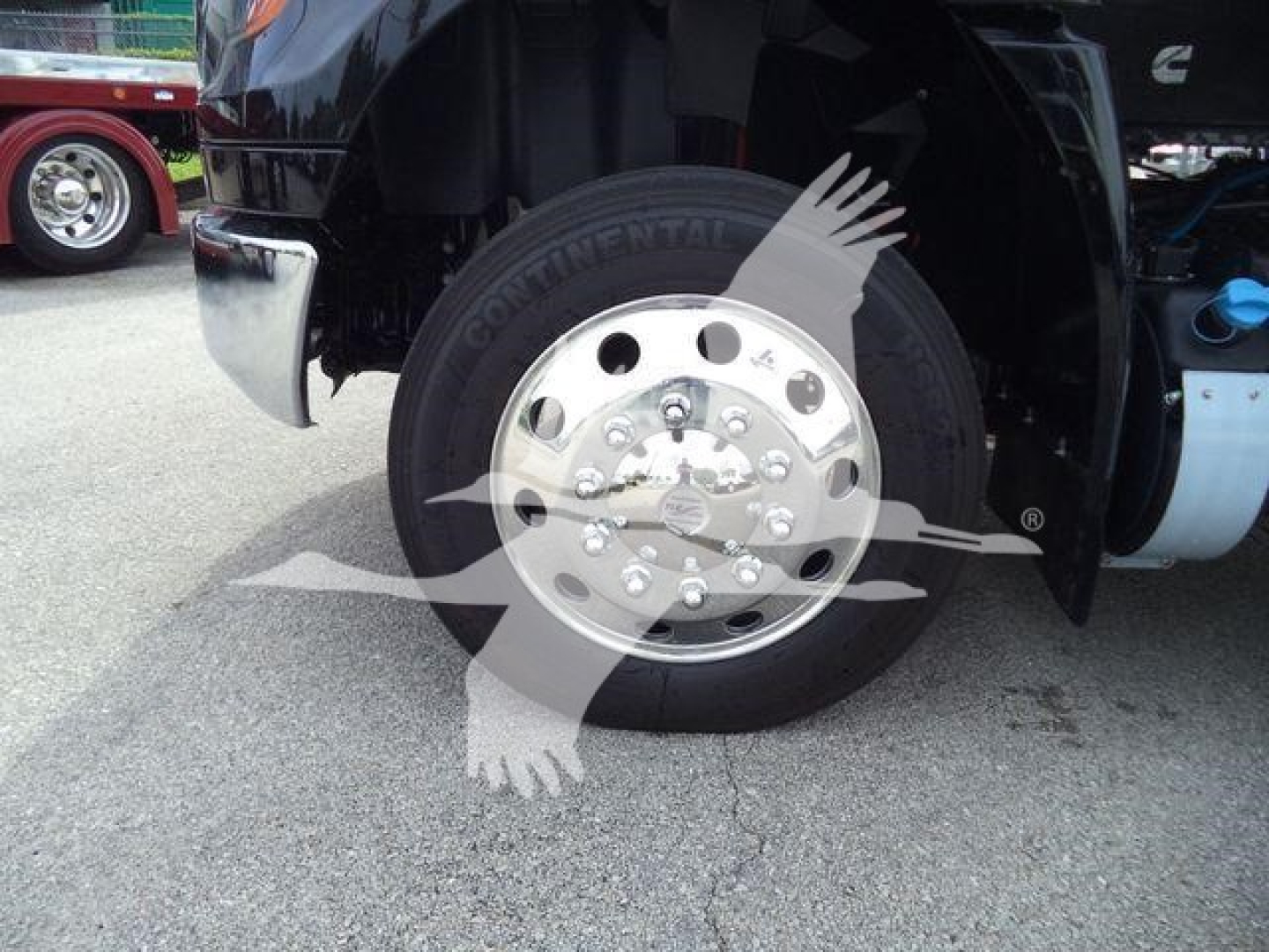 Truck front wheel and fender showing Continental tire and chrome wheel; partial view of fuel tank and step; watermark overlay across wheel.