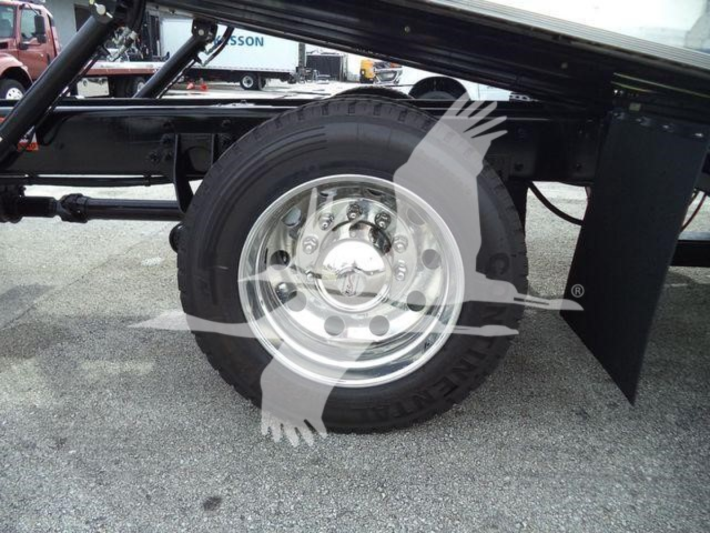 Wheel and tire on a truck chassis with splash shield and suspension components visible
