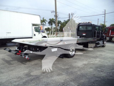 Truck bed flatbed in a rollback truck trailer with dual axles and rear ramps visible.