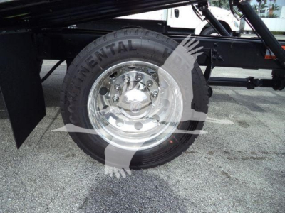 Truck wheel and tire close-up showing Continental tire mounted on polished steel rim under truck chassis.