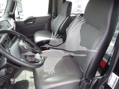 Interior of a 2026 International MV truck cab showing driver and passenger seats, steering wheel, dashboard, and doors.