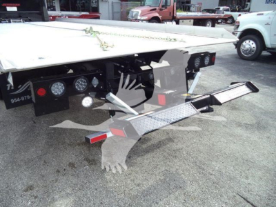 Flatbed tow truck trailer rear with steps and controls, side gauges, and hydraulic components visible.