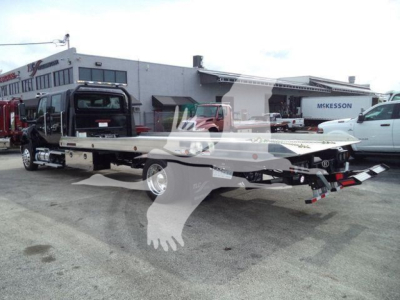 Tow truck with flatbed in a dealership lot, International MV, rollback category, stock BMVCREW22NGAF, new vehicle.