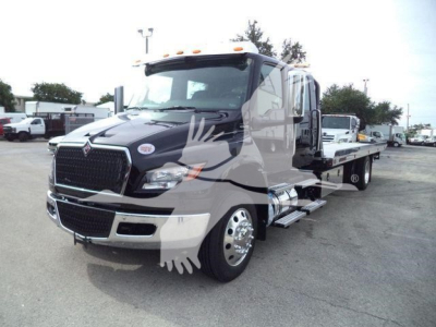 International MV rollback tow truck in showroom stance showing front grille and side step with chrome wheels.