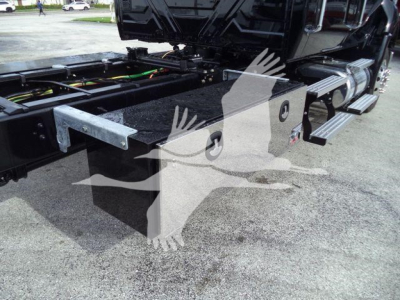 Truck chassis and side steps of a 2026 International MV rollback truck, showing undercarriage frame, hydraulic lines, and metal step rails.