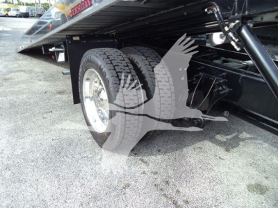 Dual rear wheels under a rollback tow truck chassis with hydraulic flatbed; visible text includes 'JERROn' or 'JERDON' on the bed edge and structural components.