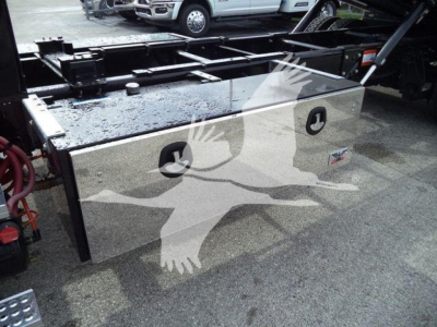 Boxed utility truck bed with polished aluminum tool/storage box mounted on chassis, with two circular access ports and logo badge visible.