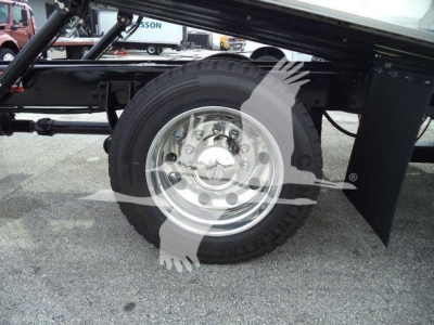 Wheel and tire on a truck chassis with splash shield and suspension components visible